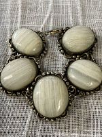 Close-up image showing five oval jasper stones with silver tone metal surrounding them, set in a chunky bracelet.
