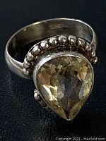 Front view of pear-shaped faceted lemon quartz set in 925 sterling silver ring with detailed beaded silver surround.