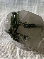 Green tourmaline crystals embedded in quartz matrix showing overall mineral specimen shape and texture.
