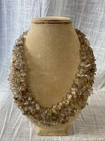 Full view of the choker necklace displayed on a jewelry stand, showing the woven multi-strand design made of inclusion quartz chips.