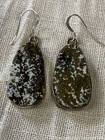 Front view of pair of jasper and sterling silver earrings placed on cream fabric.