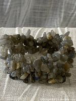 Close-up photo of a labradorite gemstone chip woven stretch bracelet showing varied colors and labradorescence effect.