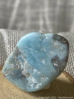 Close-up photo of raw Larimar stone showing blue and white coloration with natural rough texture