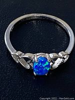 Close-up side view photo of synthetic opal ring showing band and setting details.