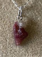 Close-up of raw pink tourmaline pendant with quartz on 925 sterling silver bale attached to chain.