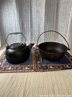 Photo of vintage cast iron kettle and pot on textiles