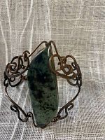 Close-up of front view of trout jasper stone encased in copper wire bracelet showing detailed wire wrapping and stone pattern.