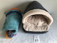 Photo showing the cat bed and folded crochet blanket side by side on a surface with marker showing number 20.