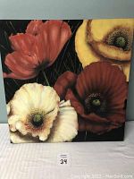Front view of a colorful 24-inch square canvas floral wall hanging showing red, yellow, and white poppy flowers on a black background.