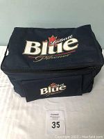 Full front view of navy insulated cooler bag with Labatt Blue Pilsener logo on top and front pocket.