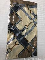 Sealed ladies scarf showing beige background with gold and blue belt and chain pattern.