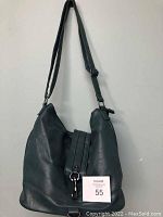 Front view of teal slouch bag showing adjustable shoulder strap, front decorative strap with clasp, and general shape and condition.