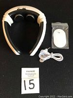 Top view of the electric pulse neck massager device with two electrode pads, remote control in plastic bag, USB charging cord, and MaxSold auction card.