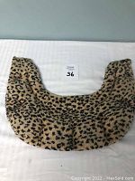 Leopard print side of the U-shaped shoulder heating pad laid flat on a white surface.