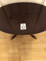 Top view of the oval coffee table showing smooth polished dark wooden surface with a display card marked '10'.