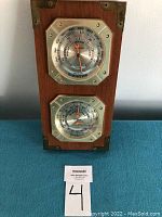 Full view of wooden panel with two circular dials for barometer and hygrometer.