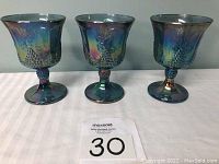 Photo of three iridescent blue carnival glass goblets displayed side by side, showing the shape and color of the lot.