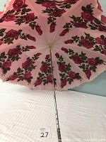 Photo showing the underside of the umbrella with pink rose pattern and silver handle with rhinestones.