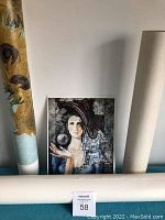 Four rolled vintage prints standing upright with a loose print of woman sitting in front