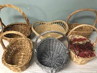 Six wicker baskets grouped together showing variety of sizes, colors and one with dried moss and grasses.