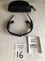 Black Bluetooth sunglasses laid out open with built-in ear speakers visible, along with carrying case and manual.