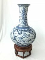 Front view of vintage blue and white Asian porcelain vase on wooden and marble stand showing floral and tree designs