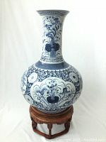 Full view of blue and white porcelain vase on wooden and marble stand