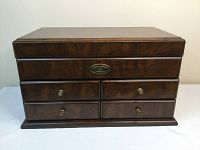 Front view of the wooden jewelry box showing four drawers and wooden finish.