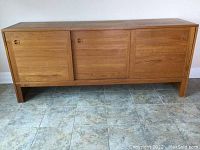 Front view of teak sideboard showing three sliding doors and straight legs