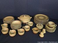 Full set of Ekco stoneware in Canoe pattern arranged on black background, showing cups, bowls, plates, covered casserole, and condiment pieces.