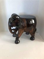 Front side view of the elephant plant stand showing carved trunk and legs with polished dark wood finish.