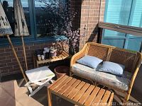 Overview of loveseat, wooden tables, white table, plant pots and decorative branch