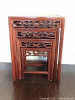 Front view of four rosewood nesting tables stacked together