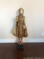 Full front view of the gilded wood Buddha statue on base