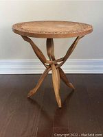 Full view of carved three-legged wooden table showing cobra-inspired base and round tabletop with carved details.