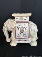 Side view of ceramic elephant plant stand showing carved panel and textured surface.