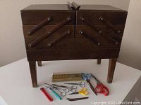 Closed wooden sewing box with assortment of scissors and tools placed in front