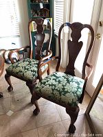 Pair of wooden dining armchairs with carved shell crest and green damask seats shown from angled front view