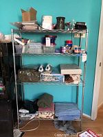 Full view of metal wire rack with miscellaneous items on shelves, showing overall structure and condition.