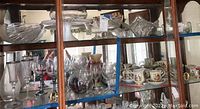 Wide view of upper and middle shelves of cabinet displaying assortment of stemmed glasses, cups, and bowls.