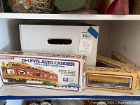 Bi-level auto carrier box and other Life-Like model train item boxes on shelf.