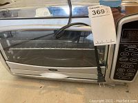 Front view of Oster toaster oven showing glass door, Oster branding, and power cord.