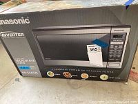 Closed Panasonic microwave oven box showing model and features.