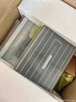 Rotisserie oven visible inside partially opened packaging with foam padding.