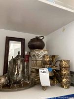 Silverplated tea set and decorative items on shelf including candle holders and mirror