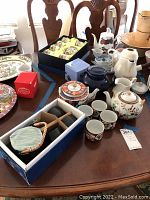 Photo showing variety of tea cups, boxed tea sets, and multiple teapots including a white and blue floral teapot