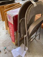 Photo shows 2 folded Samsonite metal-frame folding chairs with padded, textured grey seats and backs next to a boxed 5 piece tray table set and multiple wooden trays.