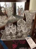 Overall view of decanter, vase, sherry glasses and tray displayed on wood surface in front of mirror
