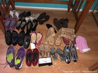 Full image showing 15 pairs of women's shoes including sneakers, boots, flats and sandals, plus bow ties and a pink hat in background.