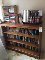 Overall view of wooden bookshelf with multiple shelves and top stacks of books